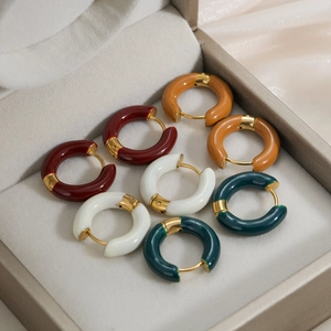 Detailed macro view of four enamel hoop earrings in rich autumn colors on satin background