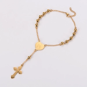 Macro shot of gold stainless steel rosary bracelet with heart pendant and cross charm
