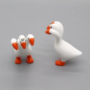 Macro detail of quirky three-headed white goose charm with orange beak and metal ring