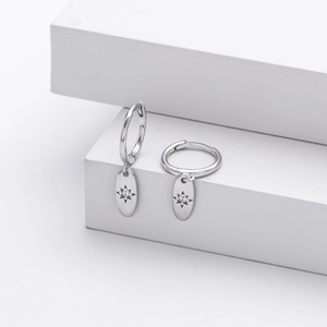 Detailed close-up of S925 silver octagonal star earrings on white geometric stands