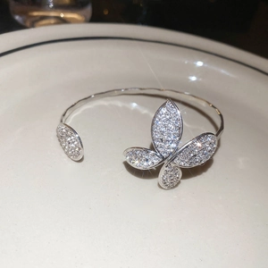 Detailed close-up of a silver open cuff bracelet featuring a sparkling diamond-set butterfly