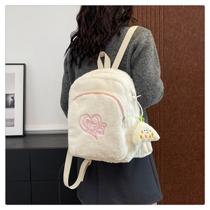 Dettaglio dello zaino in peluche bianco con ricamo a cuore rosa e ciondolo fungo