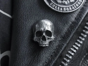 Close-up of vintage silver skull badge pinned on black leather jacket with gothic details