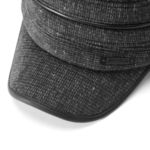 Dettaglio del tessuto in misto lana grigio scuro con logo metallico e bordo in pelle