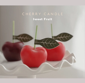 Detalle macro de velas aromáticas con forma de cereza en una bandeja de cerámica blanca