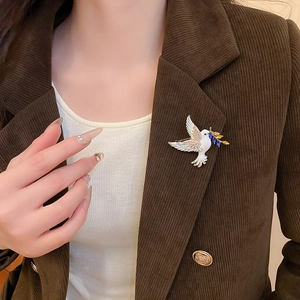 Detail of peace dove brooch with crystals and enamel pinned on a brown corduroy jacket lapel