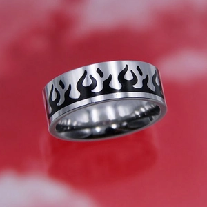 Close-up of titanium steel ring with black flame patterns on a red background