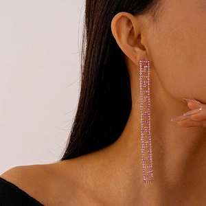 Close-up of elegant long geometric earrings with sparkling pink rhinestones on a model