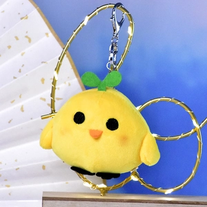 Detailed close-up of a cute yellow plush chick keychain featuring a small green sprout