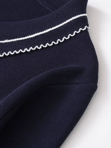Detail shot of navy blue knit fabric with white contrast wavy stitching and seams