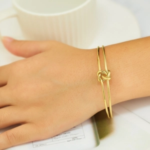 Detailed close-up of 18k gold-plated double-layered knotted cuff bracelet with matte texture