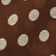 Vue détaillée du tissu en mousseline marron avec des motifs à pois blancs et des textures