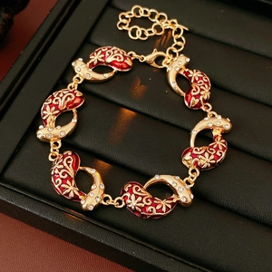 Detail of vintage gold bracelet with red enamel and zircon on black jewelry stand