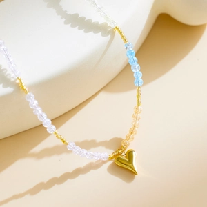 Colorful beaded necklace with golden heart pendant on a minimalist aesthetic background