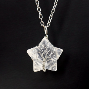 Macro shot of silver wire wrapped tree of life pattern on star shaped white crystal necklace