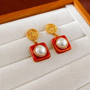 Détails de boucles d'oreilles vintage en émail rouge et perles blanches sur socle doré