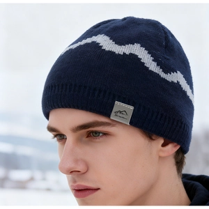 Close-up of navy knit beanie with gray mountain pattern and woven patch on a model