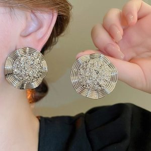 Detail of silver round earrings with geometric hammered texture and ribbed layered edges