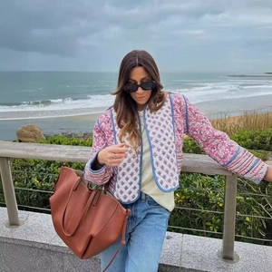 Bohemian floral quilted jacket with blue trim paired with a large brown leather tote bag