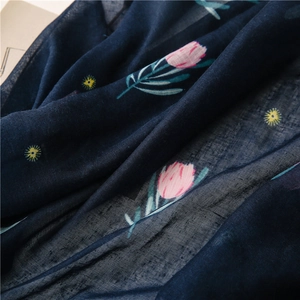 Close-up of lightweight navy cotton scarf fabric with pink floral prints and soft texture