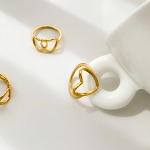 Three gold heart-shaped hollow rings shown from a 45-degree angle in minimalist setting