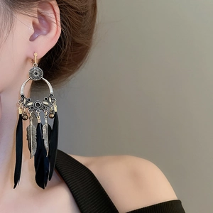 Détail de boucles d'oreilles bohèmes avec de longues plumes noires et perles rétro