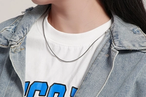 Close-up of minimalist silver snake chain necklace worn on a model with metallic shine