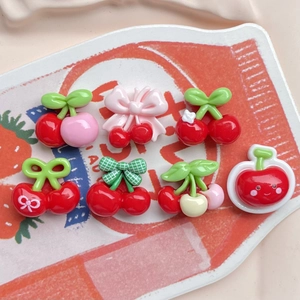 Detailed flat lay of seven mini resin cherry charms with colorful bows and cute smiley faces