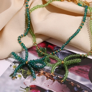 Close-up of green faceted crystal beads and golden bow pendant on double-layer necklace