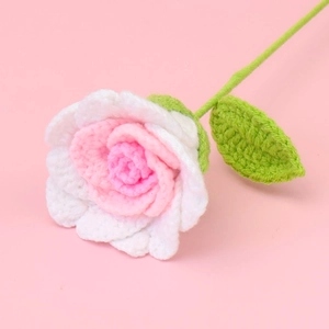 Macro detail of handmade crochet Thai rose with white and gradient pink petals on stem