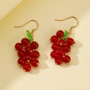 Detailed view of red berry grape earrings with green leaf accent and gold hooks