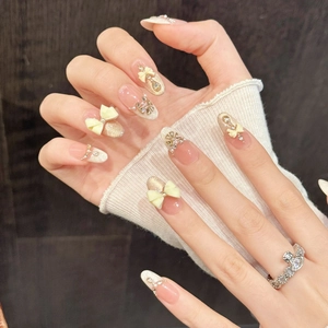 Pink and nude press-on nails with 3D bows, pearls, and rhinestones on hands