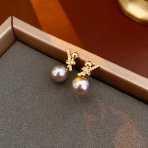 Detail of 18k gold plated bow earrings with sparkling zircon and grey-purple pearl
