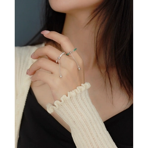 Close-up of adjustable S925 silver rings with green crystals and tassel details