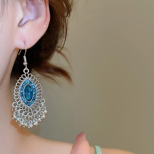 Dettaglio di orecchini vintage in argento con gemme blu ovali e eleganti nappe di perline