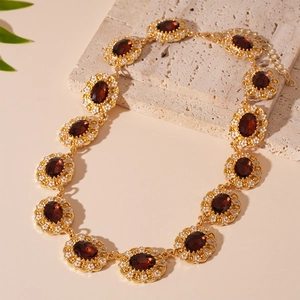 Close-up of vintage gold necklace featuring deep red gemstones and floral enamel details