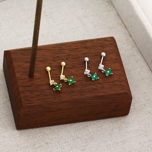 Detail of s925 silver four-leaf clover stud earrings with green zircon on wood