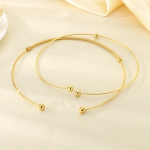 Detailed view of gold-plated twisted cable and smooth metal open collars on silk background