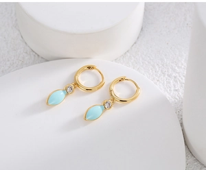 Detailed macro of gold-plated hoop earrings with light blue enamel leaf and zircon