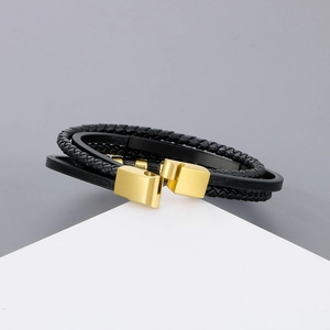 Detail of multi-layer black braided leather bracelet with gold magnetic clasp closure