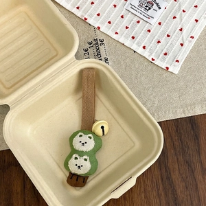 Close-up of cute cartoon bear plush charm with embroidery details and a small bell