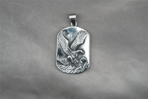 Detailed relief of an eagle and mountains on a vintage steel military pendant