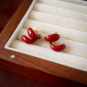 Détail macro de boucles d'oreilles rouges courbées dans un coffret en bois