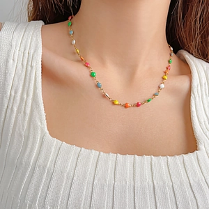 Détail des breloques cœurs colorés sur un collier en acier inoxydable doré