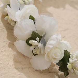 Macro shot of white fabric flowers and green leaves on a handmade bridal wreath