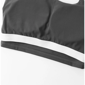 Détail de l'ourlet élastique large avec bande blanche sur le soutien-gorge de sport gris