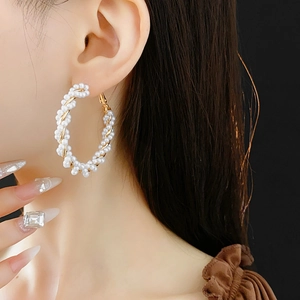 Detail of twisted white pearls on golden metal hoop earrings for elegant styling