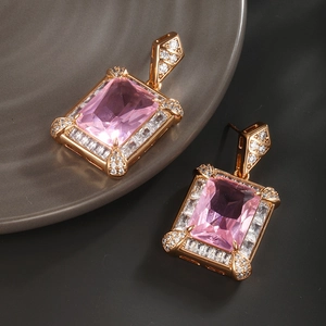 Detail of pink rectangular gemstone earrings with white zircon accents in gold plating