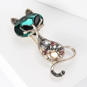 Detail of vintage cat brooch featuring large emerald crystal and multicolor rhinestones