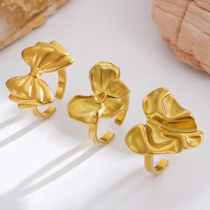 Detailed view of three 18K gold-plated rings featuring bow, flower, and petal designs